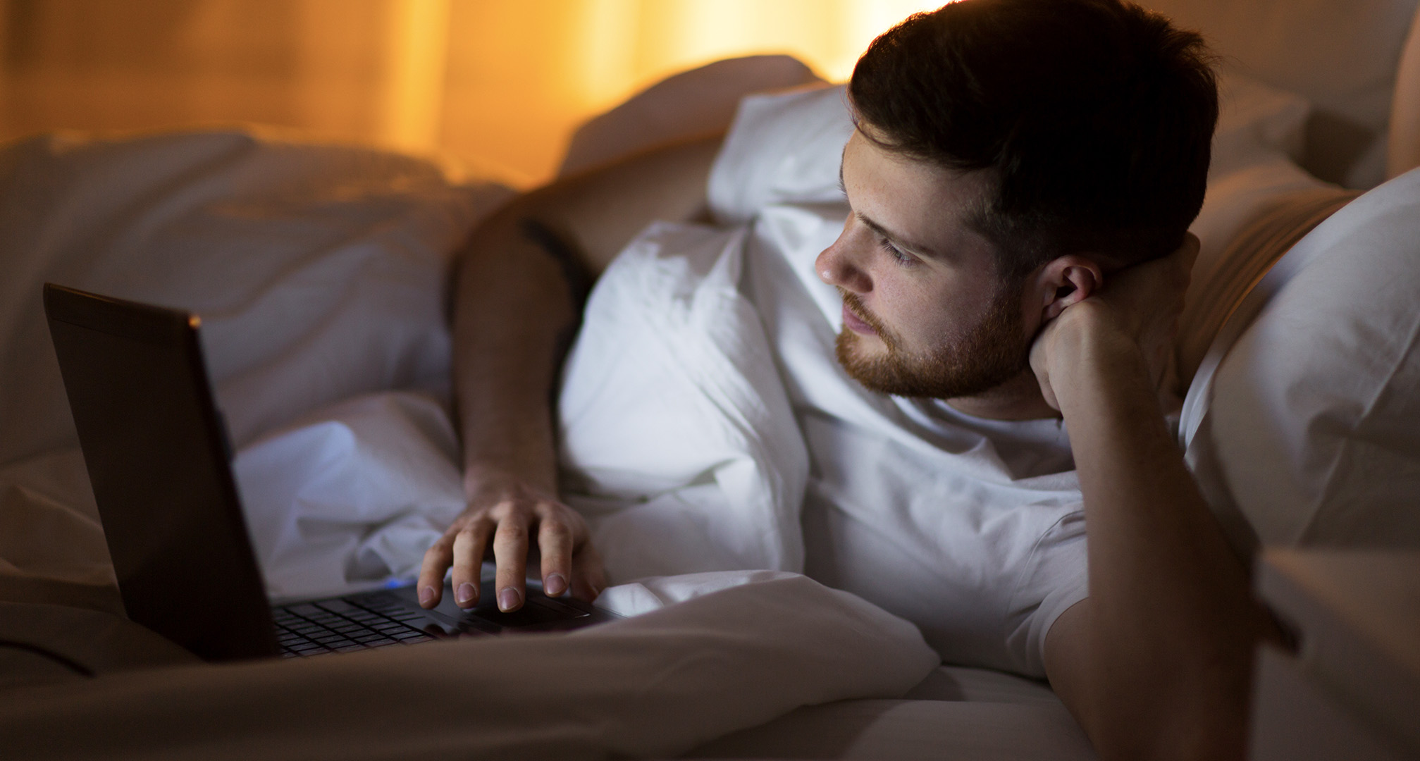 person using laptop from bed at night