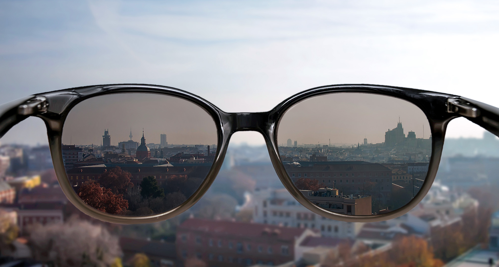 sunglasses held in front of cityscape in background